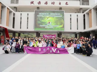 Large group of adults and children gathered outside a building, holding a Vantive banner for Arbor Day.